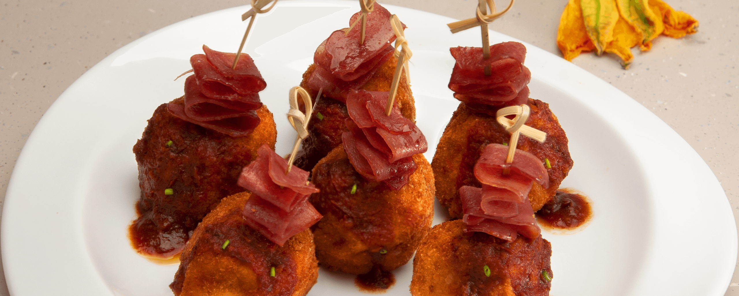Imagen de Croquetas de tocino, queso de cabra y flor de calabaza con Salsa Ranchera